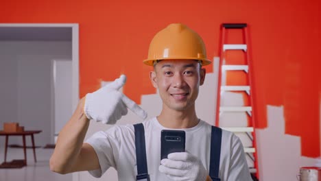 trabajador de la construcción mirando un teléfono inteligente en una habitación pintada