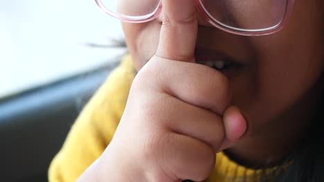 a young girl smiling with her finger on her nose