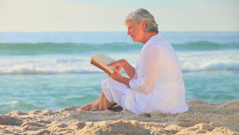 Reife-Frau-Liest-Am-Strand