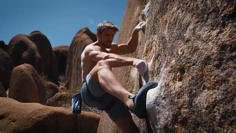 a man bouldering outdoors on a rock face under a clear sky