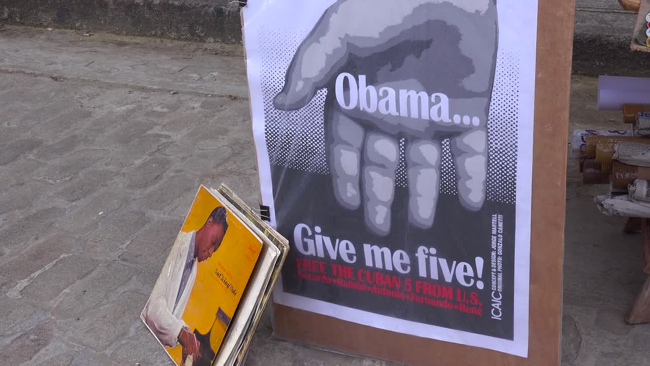 los vendedores en las calles de la habana cuba venden viejos libros y carteles de propaganda y uno que dice ¡obama dame cinco!