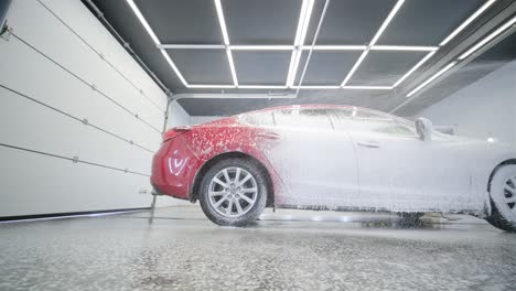 red car wash with flowing water and foam.