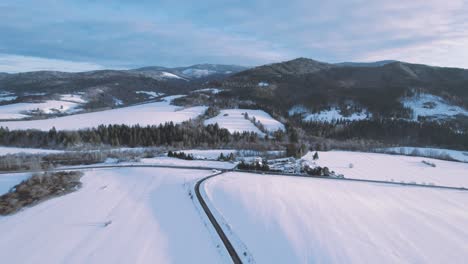 Vista-Aérea-Escénica-De-Drones-Paralela-A-Una-Carretera-Solitaria-En-Medio-De-Un-Paisaje-Montañoso-Nevado-En-Eslovaquia,-Banska-Bystrica,-Brezno