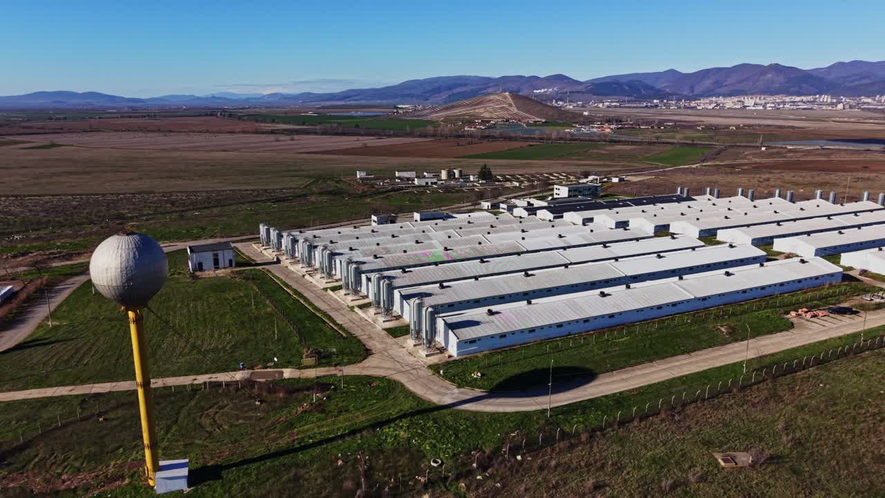 Sito industriale con campi verdi e montagne sullo sfondo