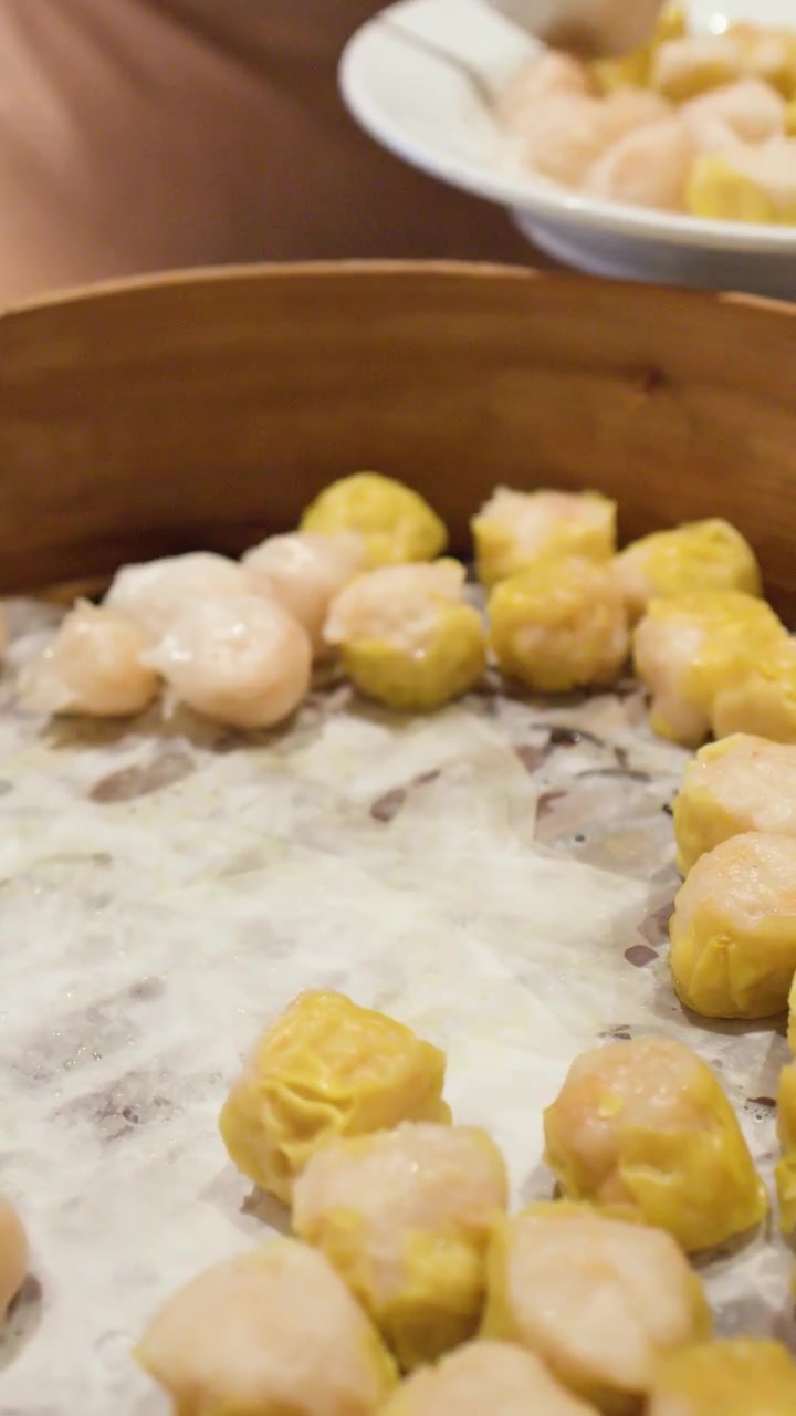 Prendere Shumai e Har Gow al vapore da un cestello di bambù per dim sum