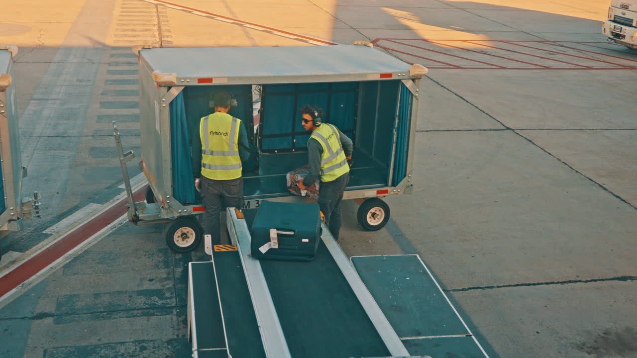 Airport Ground Staff Loading Luggage onto a Baggage Cart
