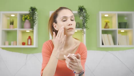 mujer joven aplicando maquillaje a la piel de su rostro.
