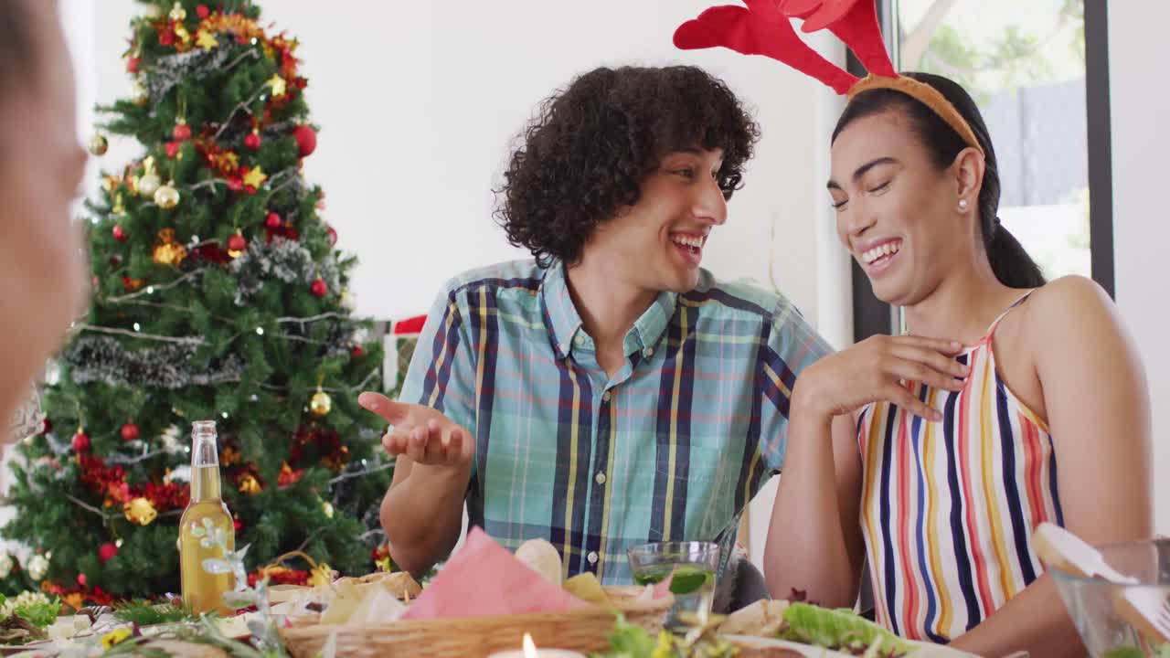 Grupo feliz de amigos diversos sentados a la mesa y cenando juntos.