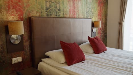 hotel bedroom with red pillows, warm lighting, and colorful wallpaper