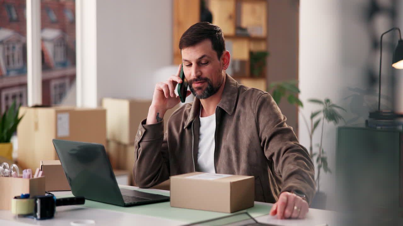 Man on Phone Call with Laptop and Package at Desk