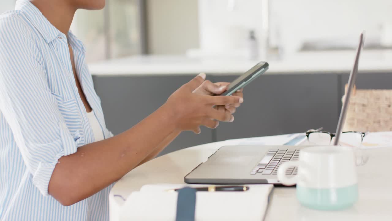 스마트폰과 노트북, 슬로우 모션으로 테이블에 앉아 있는 아프리카계 미국인 여성