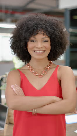 vertical video of portrait of biracial businesswoman with arms crossed smiling at office