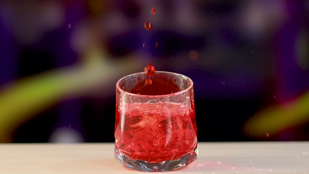 A vibrant Negroni cocktail is poured into a glass, captured in slow motion with dynamic lighting and colorful background