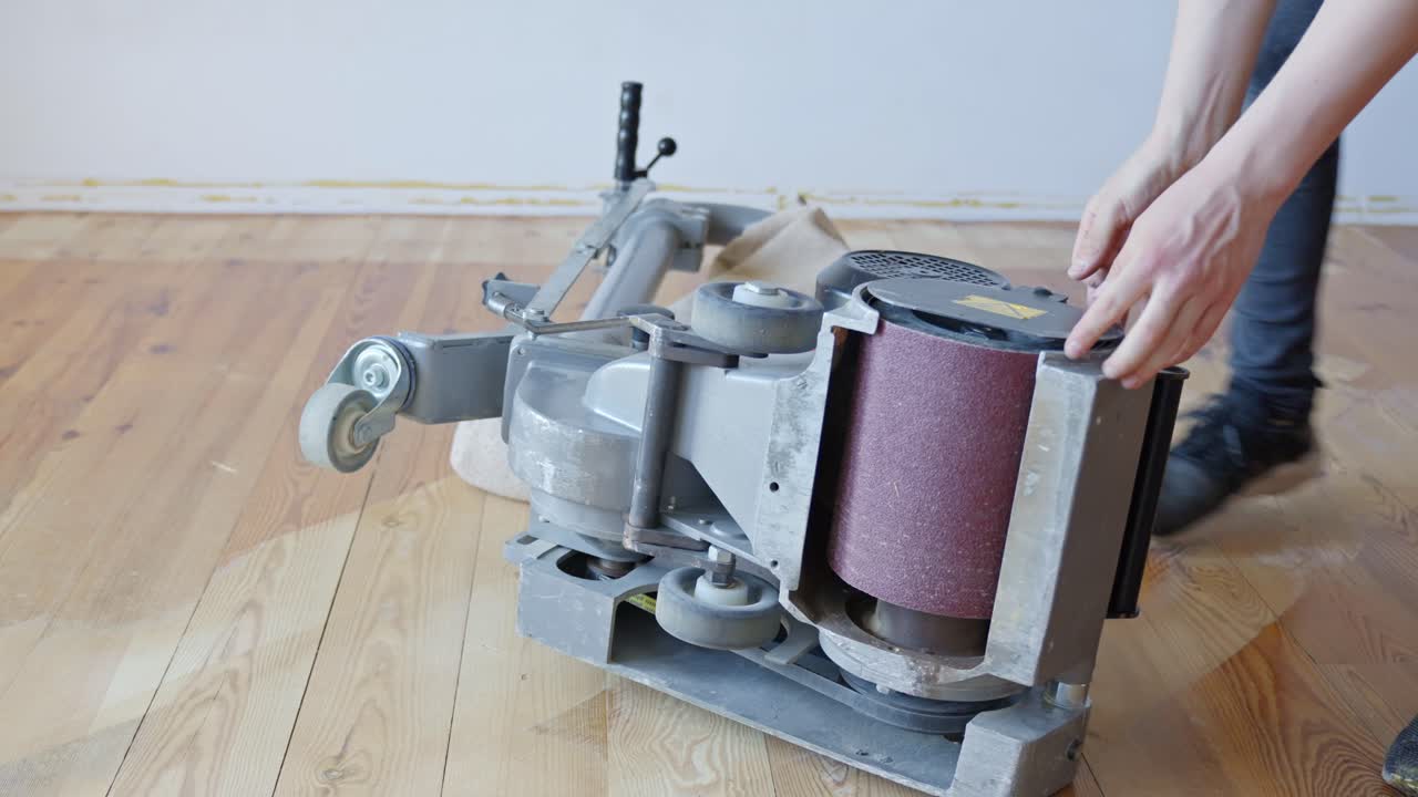 Person inspects and changes sanding paper of industrial machine at home