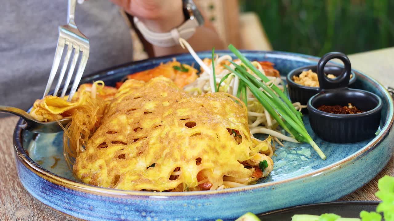 세라 접시 에서 파드 타이 를 먹는 사람