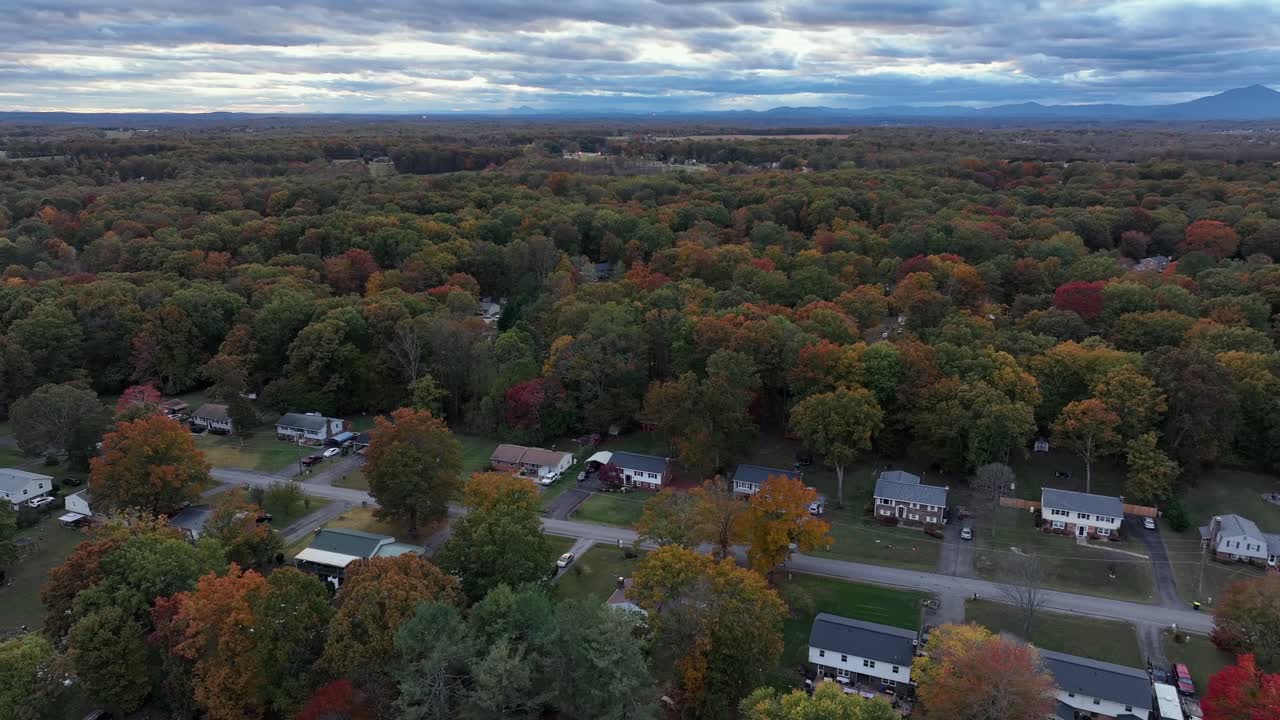 One family house neighborhood in quiet suburb district of town. Forest landscape with multi-colored tortes in suburb. Aerial wide shot. Clouds at morning sky in USA