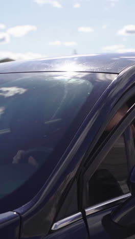 bearded man in luxury car. handsome guy in sunglasses and fashionable jacket coming out of the black car on white canyon background. slow motion. vertical video