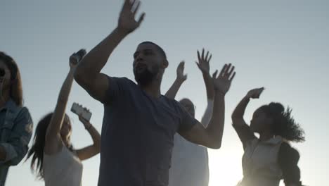 Smiling-young-people-dancing-with-raised-hands-in-park