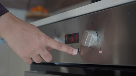 a close-up of a person setting the timer on an oven.