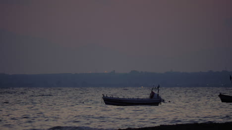 Evening-scene-of-sea-with-moored-boat-rocking-on-waves