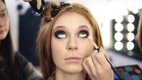 Front-Footage-Of-A-Blonde-Beautiful-Model-Sitting-And-Looking-Up-While-Make-Up-Artist-Finishing-Her-Smoky-Eyes