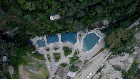 Aerial-top-down-ascending-and-rotating-view-of-natural-hot-springs-of-Colcamayo-in-Peru-and-people-bathing