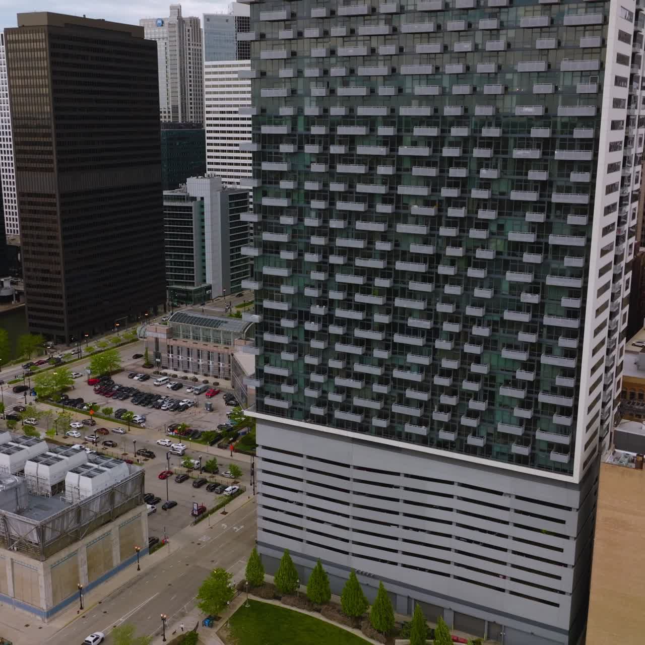 Multi- storied building with different balconies and parking lot beside. Drone footage rising to the top of the beautiful house