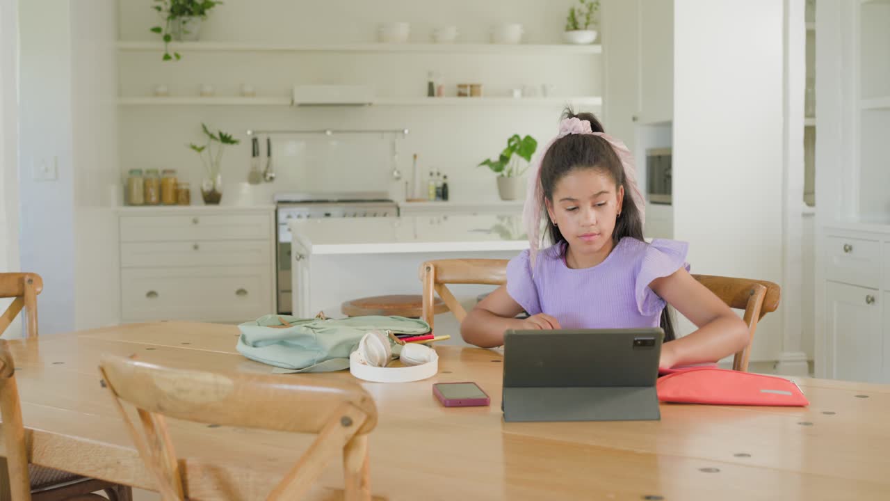 ダイニングテーブルで、アフリカ系アメリカ人の子供がタブレット、赤いフォルダーと共に薄緑色のバックパックに荷物を詰めている。余白あり。
