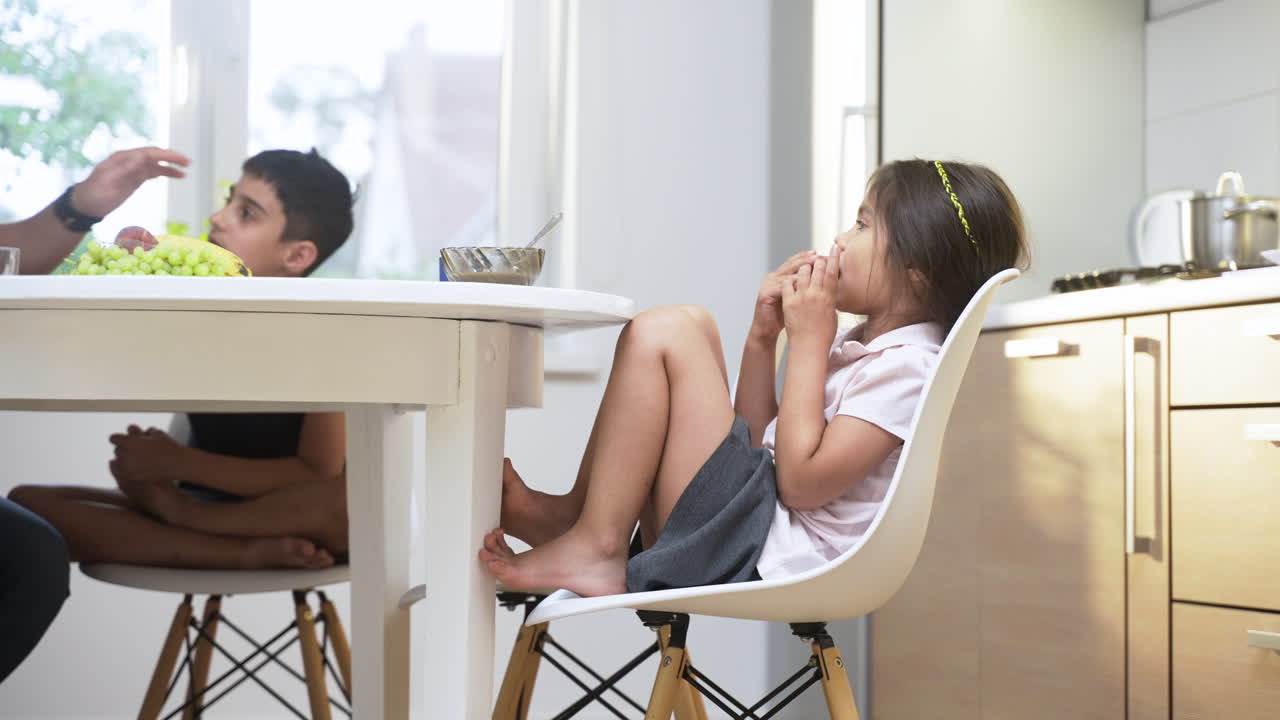 아침 식사를 하는 작은 소녀의 측면 시각.