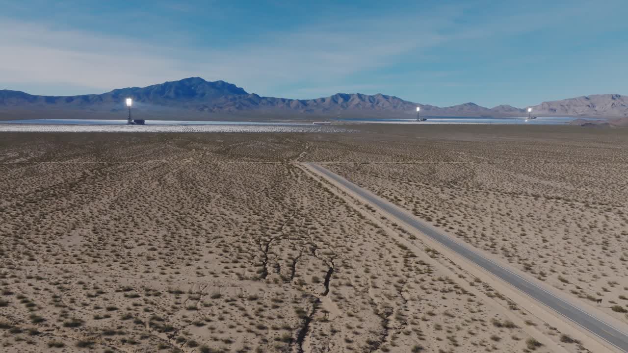 Lav høyde drone filmopptak som trekker tilbake til en bred oversikt over Ivanpah solenergianlegg i Mojaveørkenen, og avslører soltårn og heliostatfelt som produserer fornybar energi
