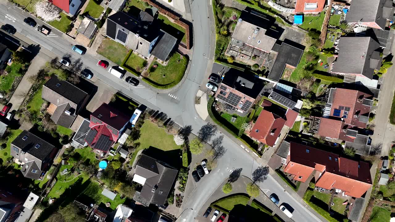 American housing area with noble single Family houses and solar panels on roof. Sunny day in spring season. Cars on street. Swimming pool in garden. Aerial top down flyover shot. Serene atmosphere.