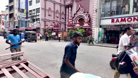 street view of the jami ul alfar mosque in colombo, sri lanka, with people walking and a tuk tuk passing by