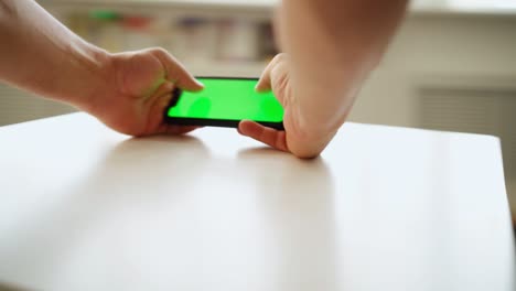 close-up, a man uses smartphone with a green screen while standing at the table