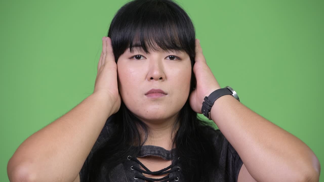 Beautiful overweight Asian woman covering ears as three wise monkeys concept