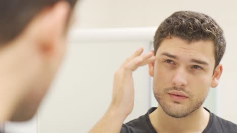 Charismatic-man-looking-at-himself-in-the-mirror.