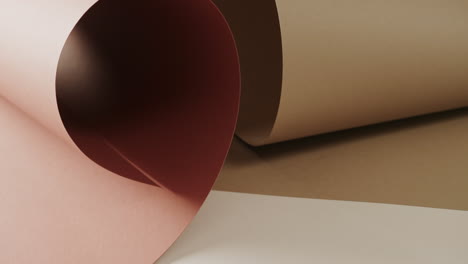 close up of two shades of brown rolled papers on white background with copy space in slow motion