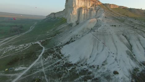 white cliffs of crimea with tourists and hot air balloons