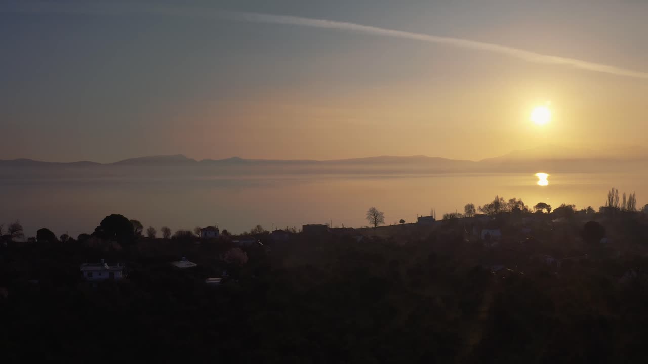 Drone flying above a hazy sea shore on golden hour sunset, bird flying over misty water surface in Lesvos, Greece