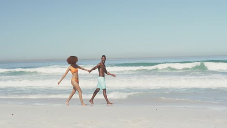 pareja afroamericana caminando por la costa