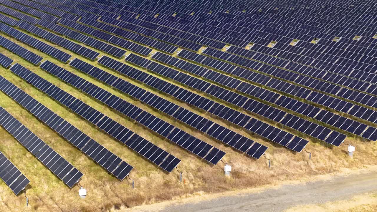 Rækker af solpaneler i sollys, dronekamera panorerer jævnt over anlæg for vedvarende energi