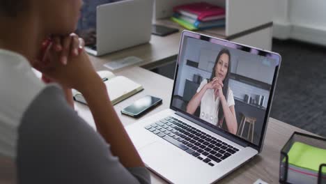Mid-section-of-african-american-woman-having-a-video-call-with-female-colleague-on-laptop-at-office