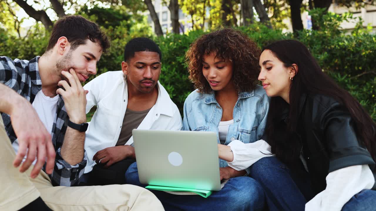 Gruppo eterogeneo di giovani adulti che collaborano al portatile all'aperto