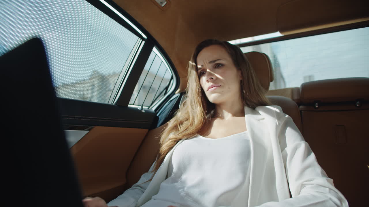 럭셔리 차에서 노트북 컴퓨터에서 나쁜 소식을 읽는 화가 난 사업가.