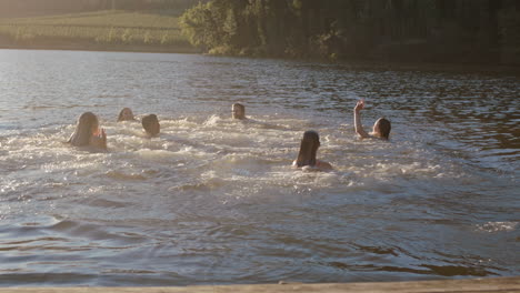 happy friends running jumping off jetty in lake at sunset having fun splashing in water enjoying freedom sharing summertime adventure