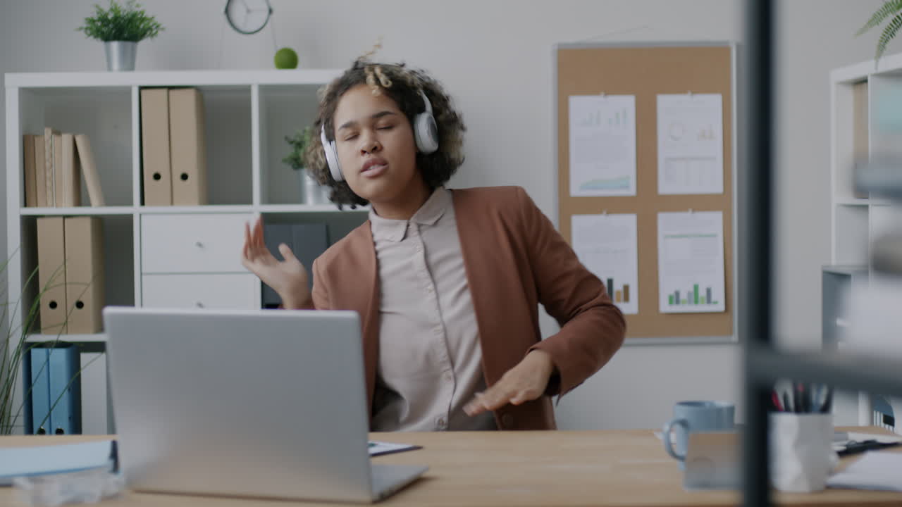Kvinde danser til musik på kontoret