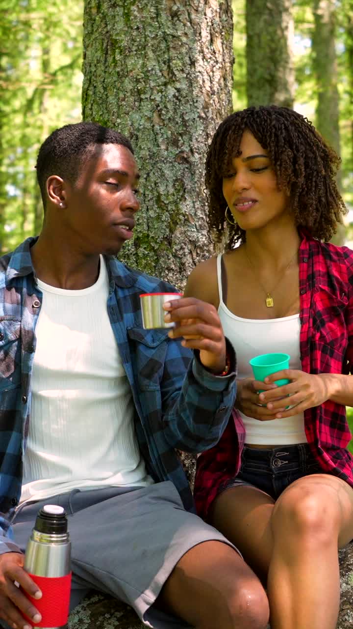 Coppia che si gode un picnic e delle bevande nella foresta