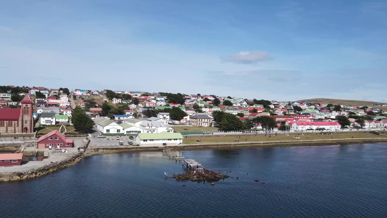 Kameraschwenk über den Stanley Harbour mit bunten Gebäuden und Küstenlinie