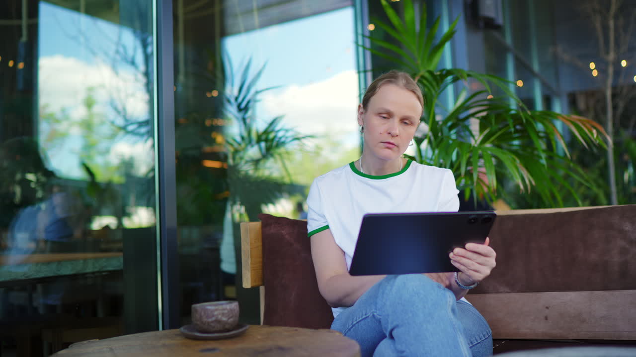 Woman Drinking Coffee and Using Tablet in a Modern Cafe