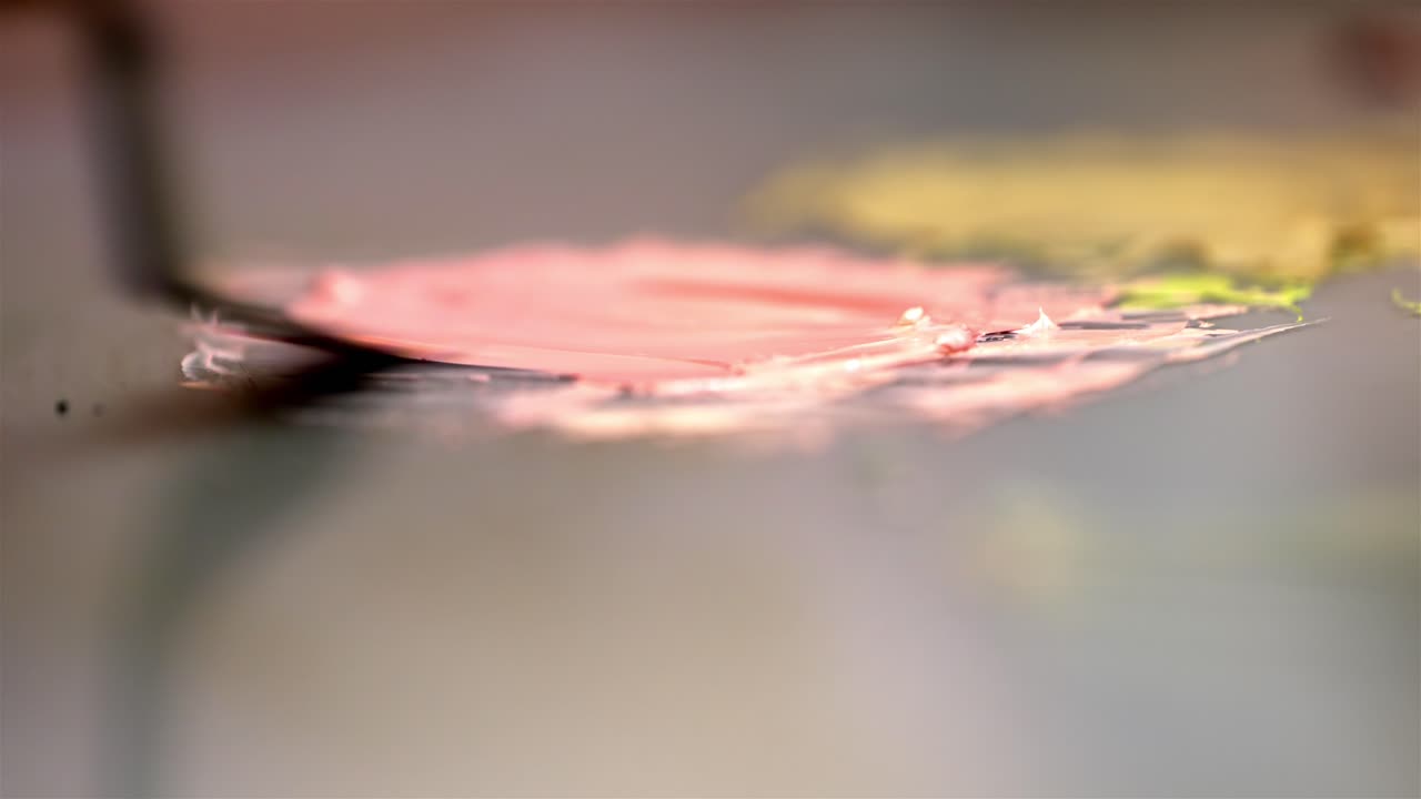 오일 페인트를 퍼뜨리고 혼합하기 위해 팔레트 칼을 사용하는 아티스트를 가로질러 라크 초점을 맞추십시오