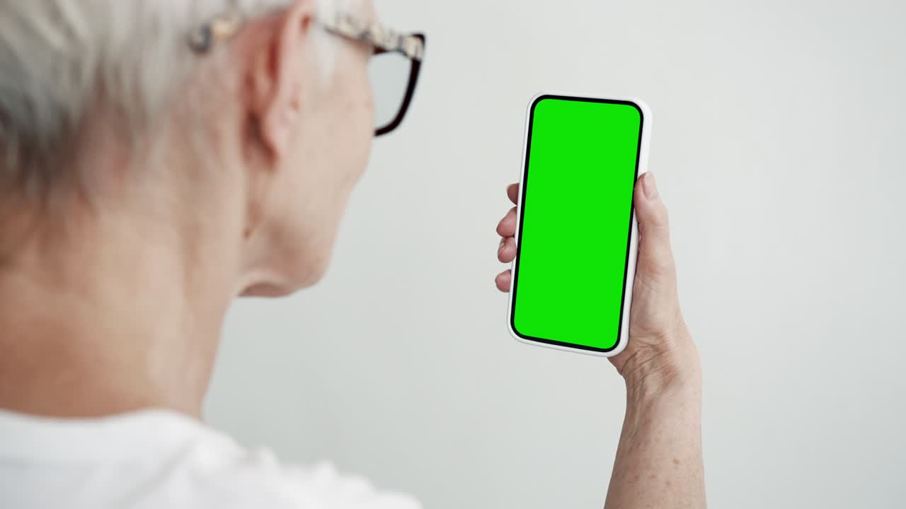 Older Person Use Smartphone with Green Screen Chroma Key Close-up. Old Female Hold in Hand Cell Phone Mock-up. Concept Watch and Show Internet Social Media, Video Calls, Read News, App, e-Shopping 4k